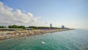 una playa con sombrillas y gente en el agua en Davka Apartments en Batumi