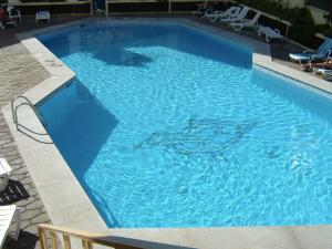 ein großer blauer Pool mit Stühlen in der Unterkunft Apartamentos Teneguia in Puerto de la Cruz