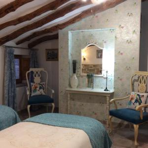 a bedroom with two blue chairs and a mirror at Los Cuatro Vientos B&B in Torre del Rico