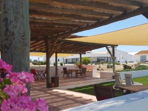 un patio con mesa y sillas bajo una sombrilla de madera en Monte Alto Agroturismo, en Campo Maior