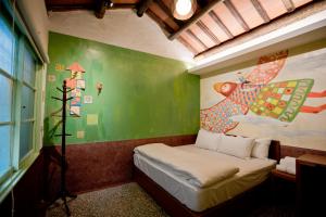 a small room with a bed and a painting on the wall at My Way House 好巷一弄民宿 in Tainan