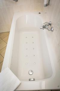 a white bath tub with a faucet in a bathroom at Studio's De Vlijt Texel in De Cocksdorp