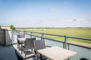 a balcony with tables and chairs and an airplane in the sky at Studio's De Vlijt Texel in De Cocksdorp