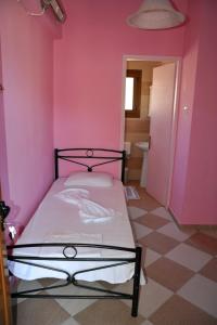 a pink bedroom with a bed in a room at Karatzas in Karfas