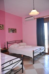 1 dormitorio con 2 camas y pared de color rosa en Karatzas, en Karfas