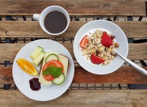 two plates of food with fruit and a cup of coffee at Coworksurf - Villa dos Irmãos in Ericeira +35 photos