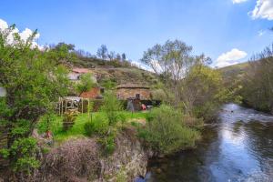 a house on the side of a hill next to a river at Casa Rural Entre Valles in Benllera