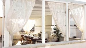 a dining room with white curtains and a table at Il Borgo in Poggiardo
