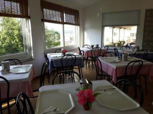 une salle à manger avec des tables et des chaises ainsi que des tables roses et blanches dans l'établissement Hotel Nido D'aquila, à La Maddalena