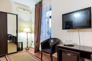 a hotel room with a flat screen tv and a chair at Hotel Corso in Buzău