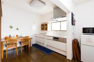 a kitchen with white cabinets and a table with chairs at A&Z Guest House 関空行南海線二色の浜駅三分 鍵付き4人部屋 in Kaizuka
