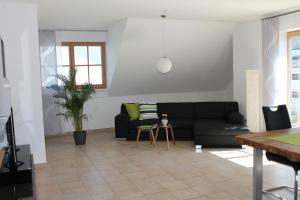 a living room with a black couch and a table at Ferienwohnung Faber mit großem Südbalkon in Essing