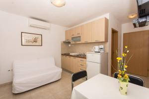 eine kleine Küche mit einem Tisch und einem weißen Kühlschrank in der Unterkunft Apartments Vukman in Trogir