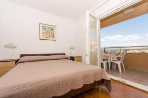 ein Schlafzimmer mit einem Bett und einem Balkon in der Unterkunft Apartments Vukman in Trogir
