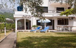 a house with chairs and an umbrella in the yard at Apartmani Jasna in Herceg-Novi