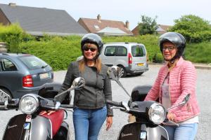 two women wearing helmets standing next to a scooter at B&B De Vroling in Wellen