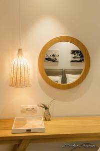 a mirror on a wall above a wooden table with a plate at Alfa Hotel in Parga