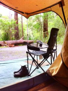 een tent met een tafel, een stoel en laarzen bij WA Wilderness - one step from nature in Pemberton