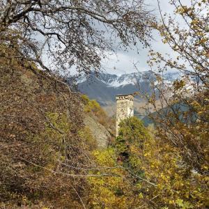 una torre de piedra en una colina con montañas en el fondo en Lagami house, en Mestia