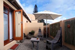 Mossel Bay的住宿－Avenues Guesthouse，庭院配有两把椅子和一把遮阳伞