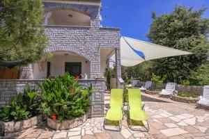 a patio with two green chairs and an umbrella at Apartments Erika in Rogoznica