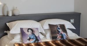 a bed with two pillows and a picture of a woman at Le Clos Du Lac - location de chambres in Veyrier-du-Lac
