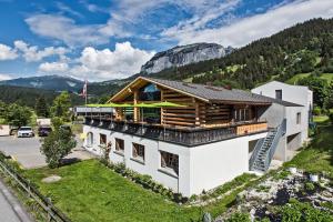 a white building with a wooden roof on a mountain at Hotel Ustria Parlatsch in Trin