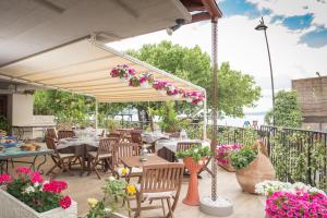 um pátio com mesas, cadeiras e flores em Malì Trevignano Piccolo Hotel em Trevignano Romano