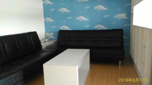 馬公市的住宿－天空格子民宿 ，客厅配有黑色沙发和白色桌子