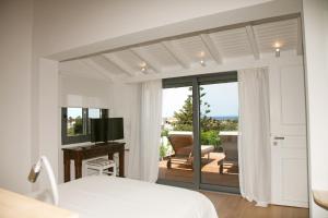 a bedroom with a bed and a balcony with a television at Artemis Village Apartments & Studios in Stavros