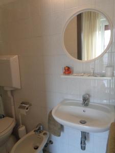 bagno con lavandino, servizi igienici e specchio di Hotel Lariana a Rimini
