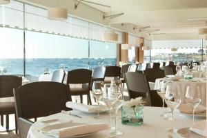 a restaurant with white tables and chairs and windows at Grand Hotel de L'Océan in Le Croisic