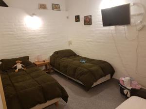 a bedroom with two beds and a tv on the wall at Complejo Duque in Puerto Madryn