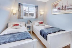 ロンドンにあるアスター ケンジントン ホステルの白い壁の客室で、ベッド2台、窓が備わります。