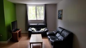a living room with two leather couches and a table at Appartement près des Plaines d'Abraham in Quebec City
