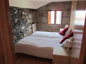 ein Schlafzimmer mit einem Bett und einer Steinmauer in der Unterkunft Casa Da Tia Em Tabuaço in Tabuaço