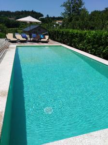 a blue swimming pool with chairs and an umbrella at Quinta de Alvarenga in Alvarenga