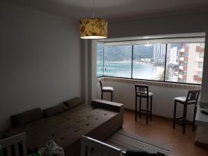 a living room with a couch and a large window at Novo lar Camboriu Park in Balneário Camboriú