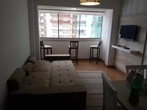 a living room with a couch and a large window at Novo lar Camboriu Park in Balneário Camboriú