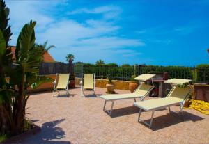 a group of chairs and tables on a patio at Costa Mediterranea Holiday Homes in Campofelice di Roccella