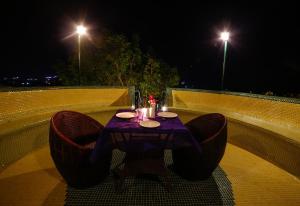 a table and chairs sitting on a balcony at night at The Colonial Manek Manor in Mount Ābu