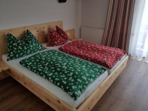 two beds with red and green pillows on them at Haus Alpenland in Sankt Andrä im Lungau