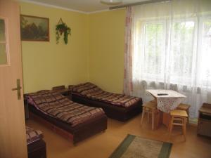 Habitación con 2 camas, mesa y ventana en Noclegi Pod Tylką, en Krościenko nad Dunajcem