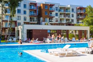 a swimming pool with people in the water and buildings at Apartamenty Polanki - visitopl in Kołobrzeg