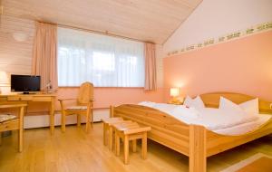 a bedroom with a large wooden bed and a desk at Hotel Haus Linden in Prerow +26 photos