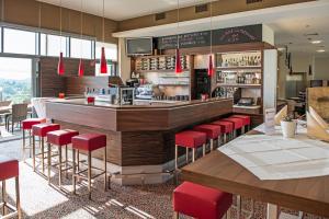 a restaurant with a bar with red stools at Hotel Liebmann in Lassnitzhöhe