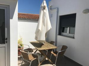 a table and chairs with an umbrella on a balcony at Avenida in Praia de Mira