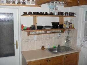 Una cocina con fregadero y estantes en la pared. en Chata Bešeňová, en Bešeňová