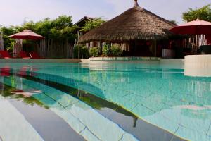 a swimming pool with a huts and a resort at Pure Plage in Lomé