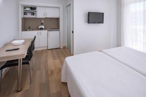 1 dormitorio con cama, escritorio y cocina en Aparthotel Marinada, en Salou